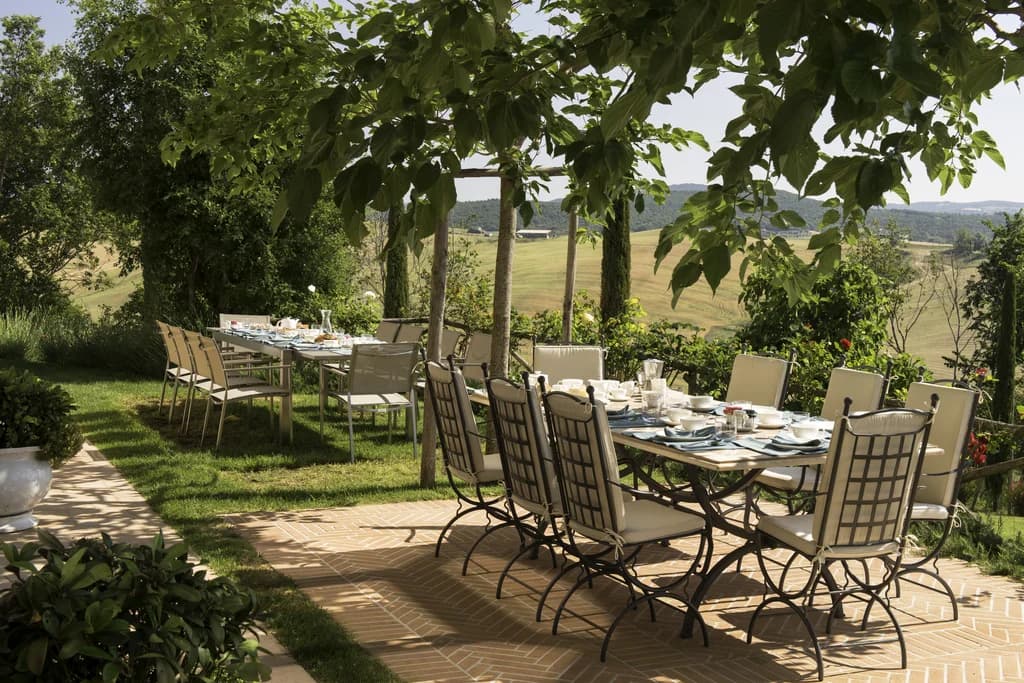 Il Pozzo outdoor dining terrace beneath tree canopy, San Quirico d'Orcia, Tuscany, Italy