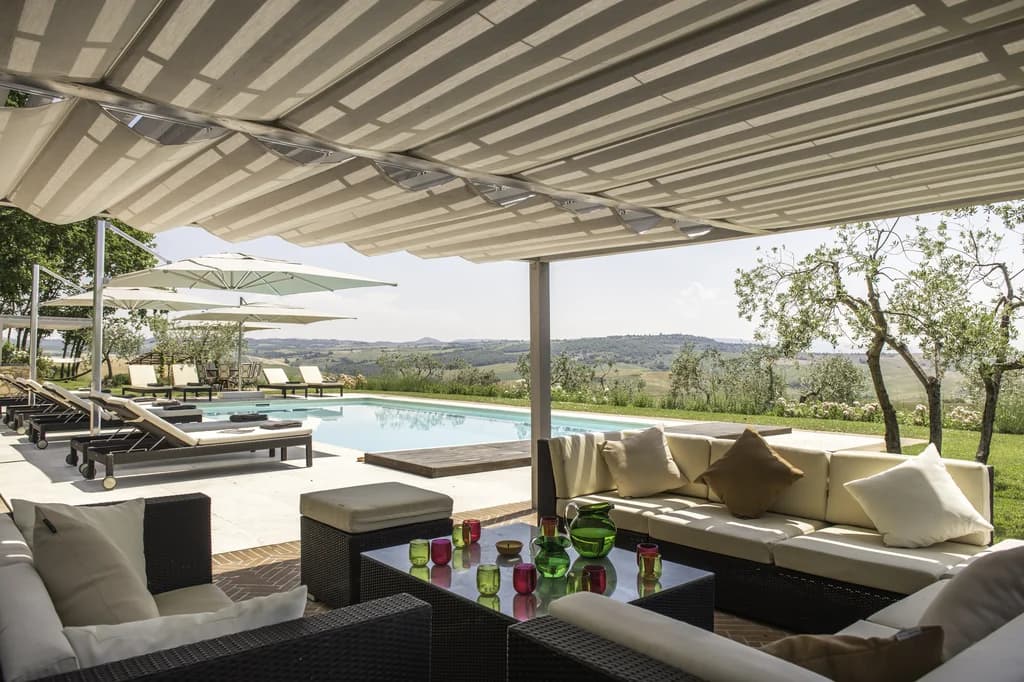 Il Pozzo poolside lounge terrace with canopy and countryside views, San Quirico d'Orcia, Italy