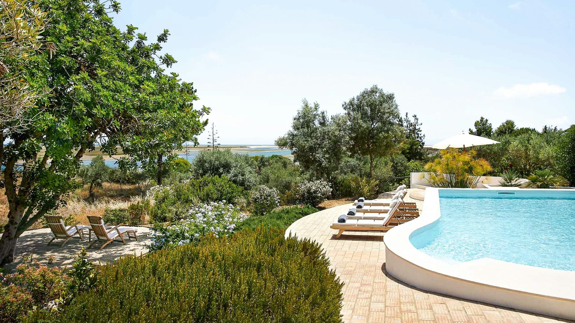 Wild Peace curved infinity pool with lagoon views and sun loungers, Tavira, Algarve, Portugal