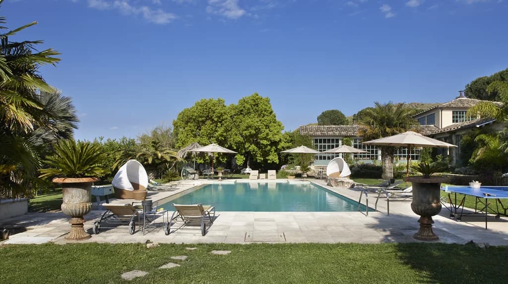 Tenuta di San Giorgio outdoor pool overview with stone urns and orangery, Scordia, Sicily, Italy