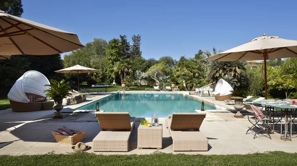 Tenuta di San Giorgio pool terrace with rattan loungers and tropical palms, Scordia, Sicily, Italy