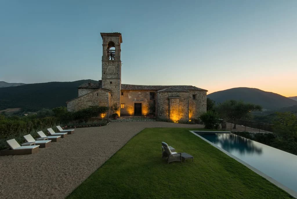 Colle Alto villa front facade at dusk with medieval bell tower and infinity pool, Umbertide, Italy