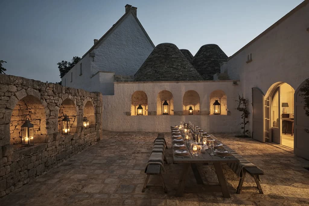 Masseria Giardini outdoor courtyard dining by lantern light with trulli, Alberobello, Italy