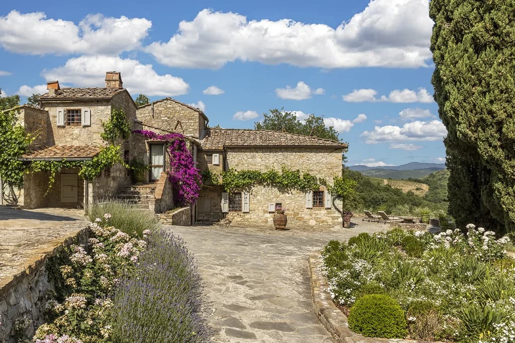 Villa Cambolli stone facade with bougainvillea and cypress trees, Castellina in Chianti, Italy