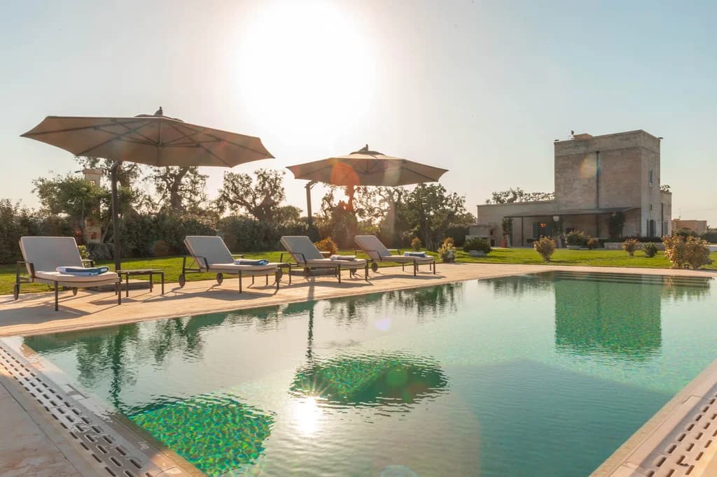 La Piccola Torre outdoor pool at golden hour with sun loungers and tower reflection, Savelletri, Italy