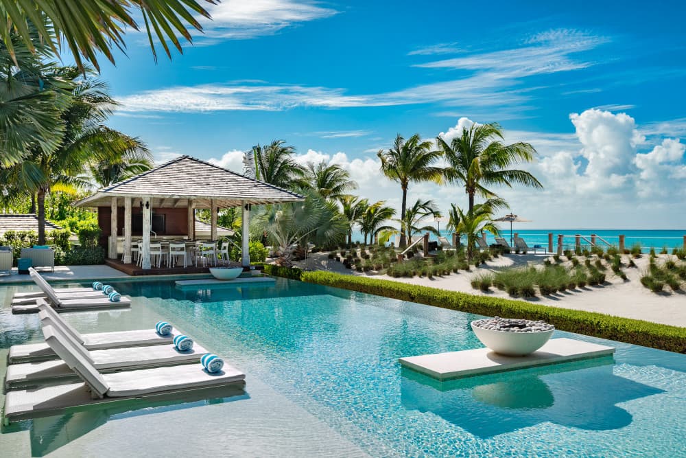 Sentosa villa infinity pool with sun loungers and thatched pavilion, Grace Bay, Turks and Caicos