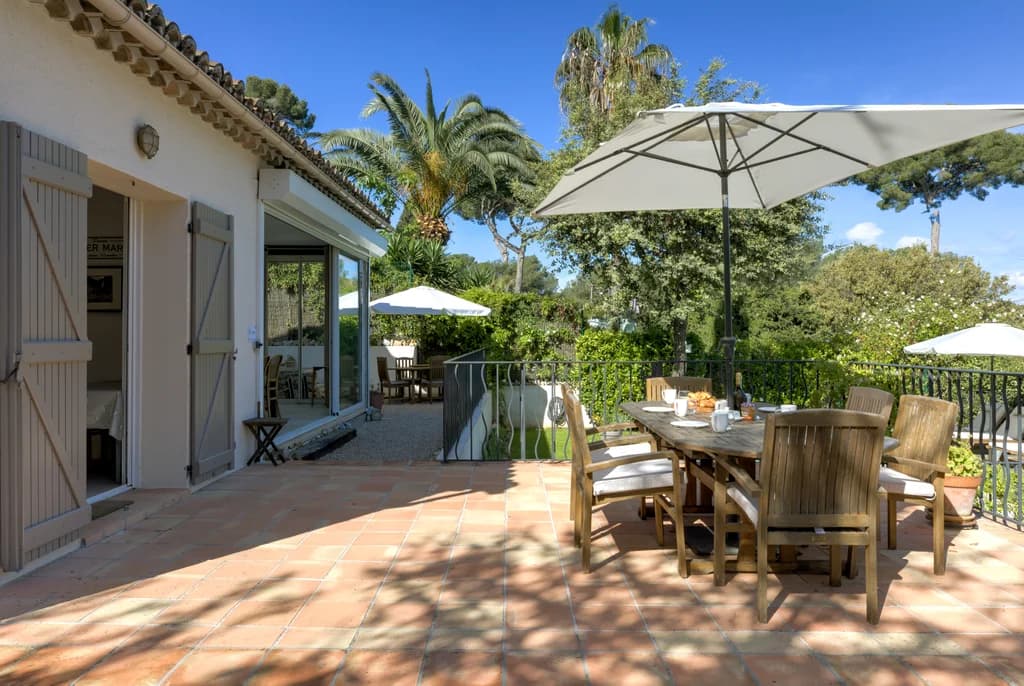 Villa Cuvier outdoor dining terrace with teak table and palm trees, Cap d'Antibes, France