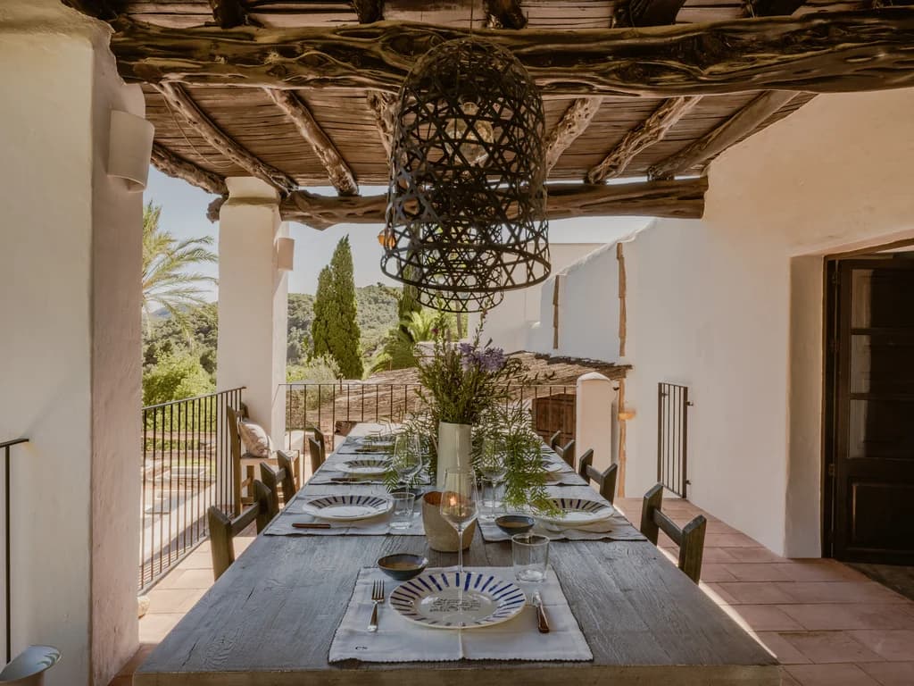 Finca Tranquila outdoor dining table with ceramic plates and wildflowers, Ibiza, Spain