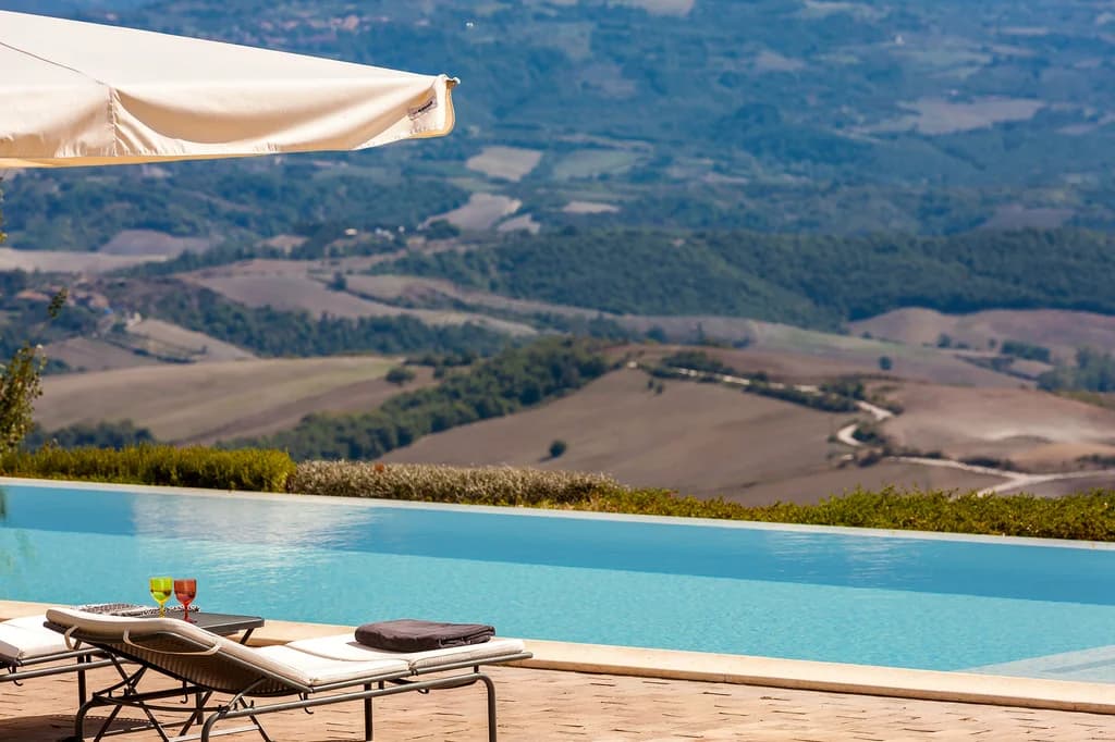 Villa Chianina infinity pool valley view with cocktail glasses overlooking Umbrian countryside, Fabro, Italy