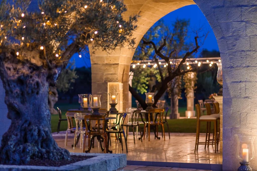 La Residenza outdoor terrace dining beneath limestone arch and olive tree, Savelletri, Italy