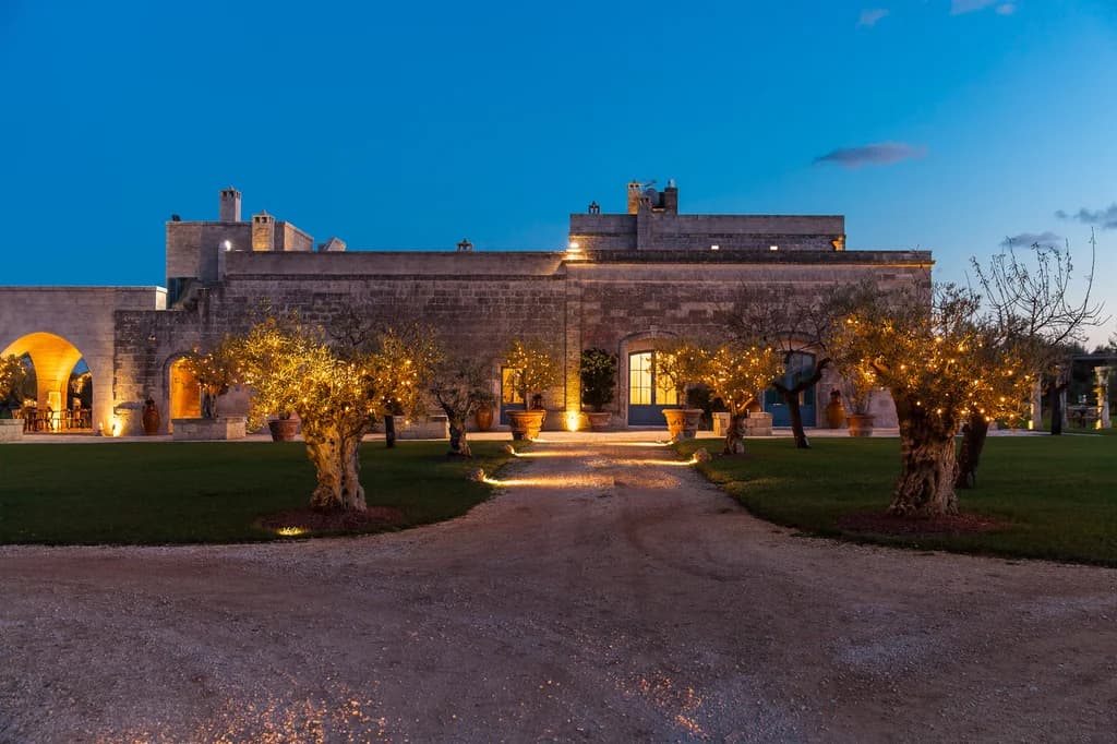 La Residenza villa entrance driveway with fairy-lit olive trees at dusk, Savelletri, Italy