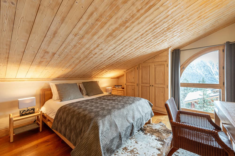 Courchevel 168 guest bedroom with pitched pine ceiling and arched alpine window, Courchevel 1850, France