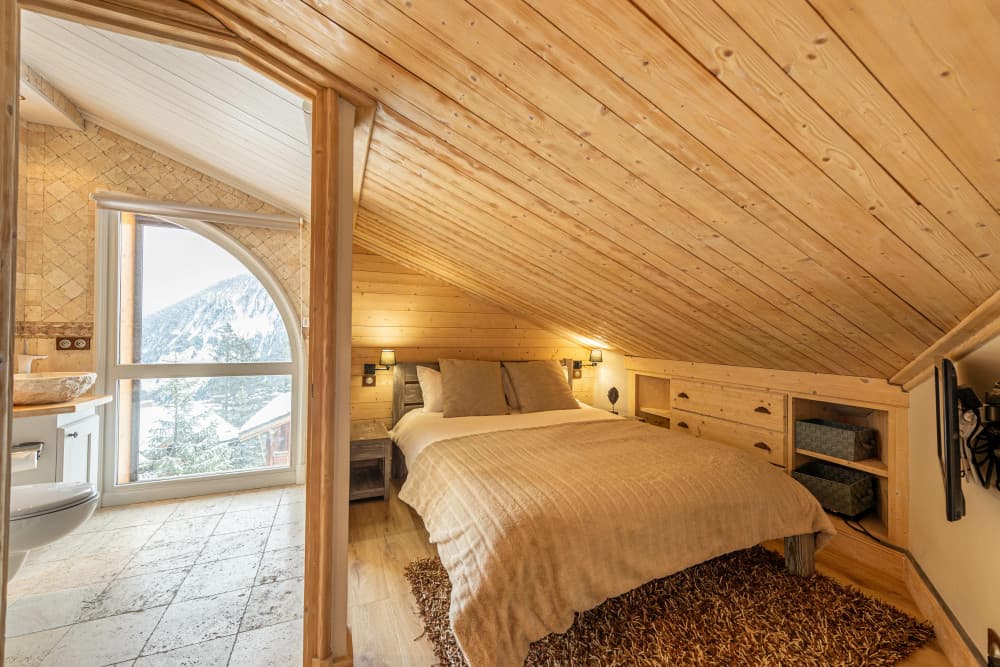 Courchevel 168 master bedroom with wood-clad ceiling and arched alpine window, Courchevel 1850, France