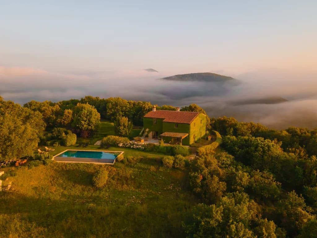 Villa Elceto aerial view above clouds at sunrise, elevated Umbrian hillside setting, Umbertide, Italy