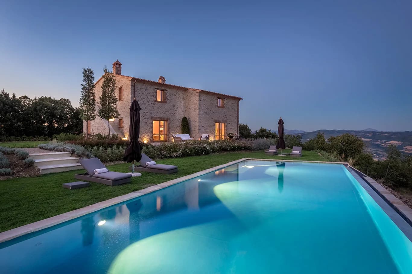 Villa Elceto illuminated stone facade and turquoise pool at dusk, Umbertide, Umbria, Italy